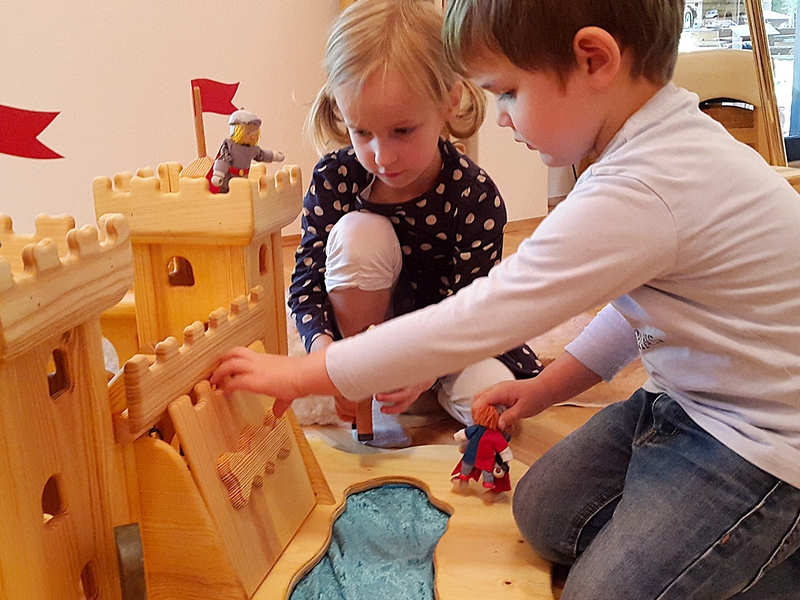 Spielende Kinder mit Holzburg Begeisterte Kinder beim Spielen mit Holzburg